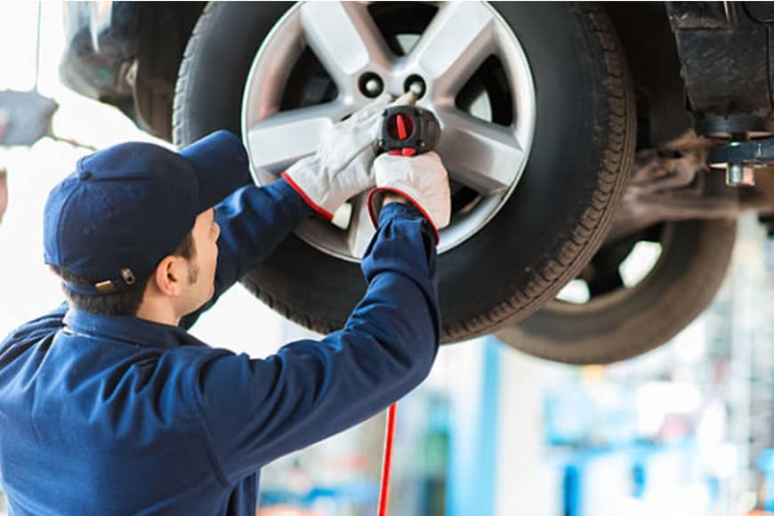 A man is working on the tire of his car.